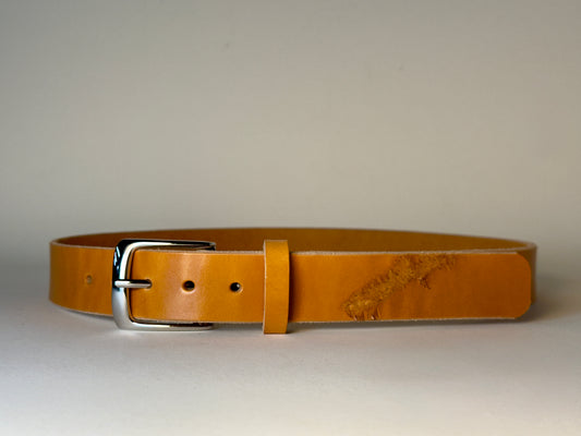 Golden honey leather belt with a silver buckle on a light gray background