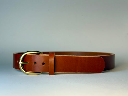 Reddish brown leather belt with a gold buckle on a gray background