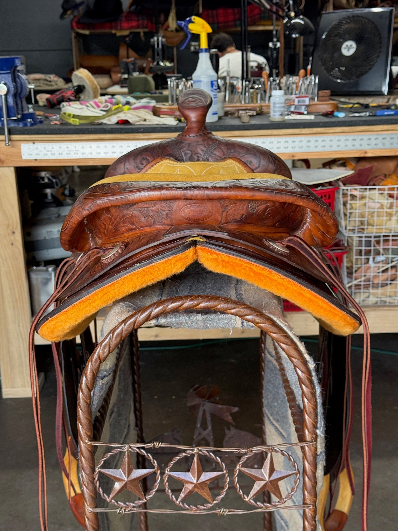 Brown leather saddle with star design on a workshop background