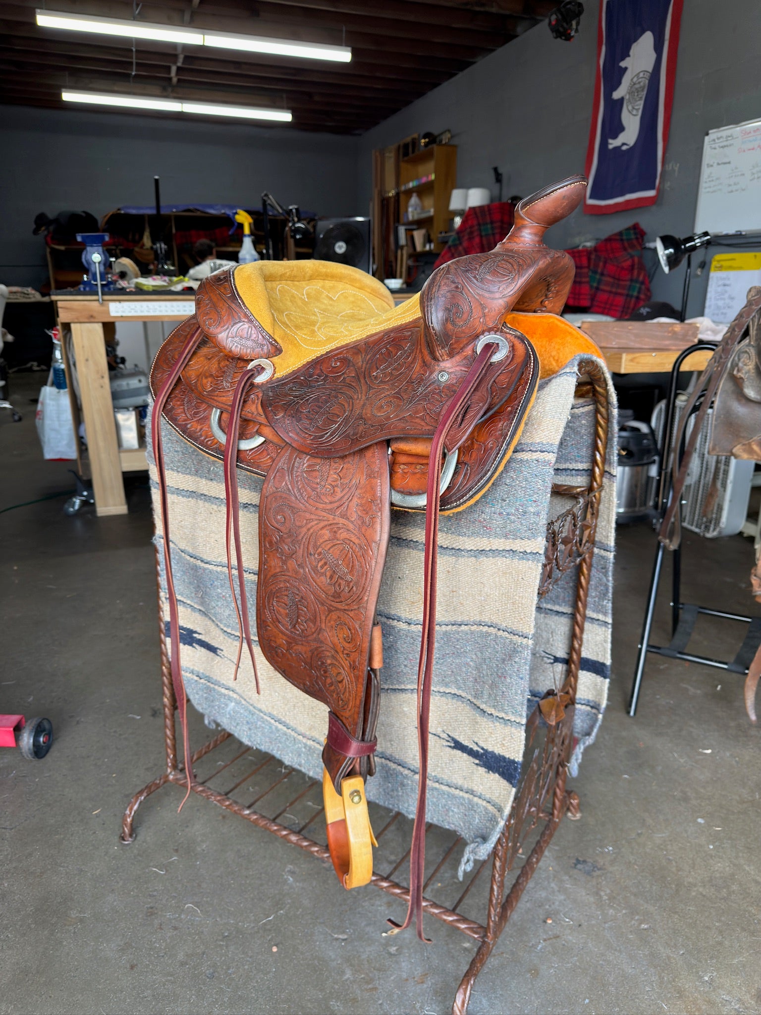 Brown leather saddle on a metal stand in a workshop setting