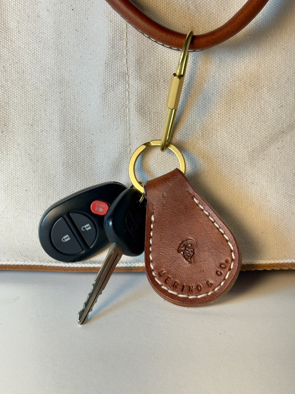 Brown leather keychain with keys on a beige background