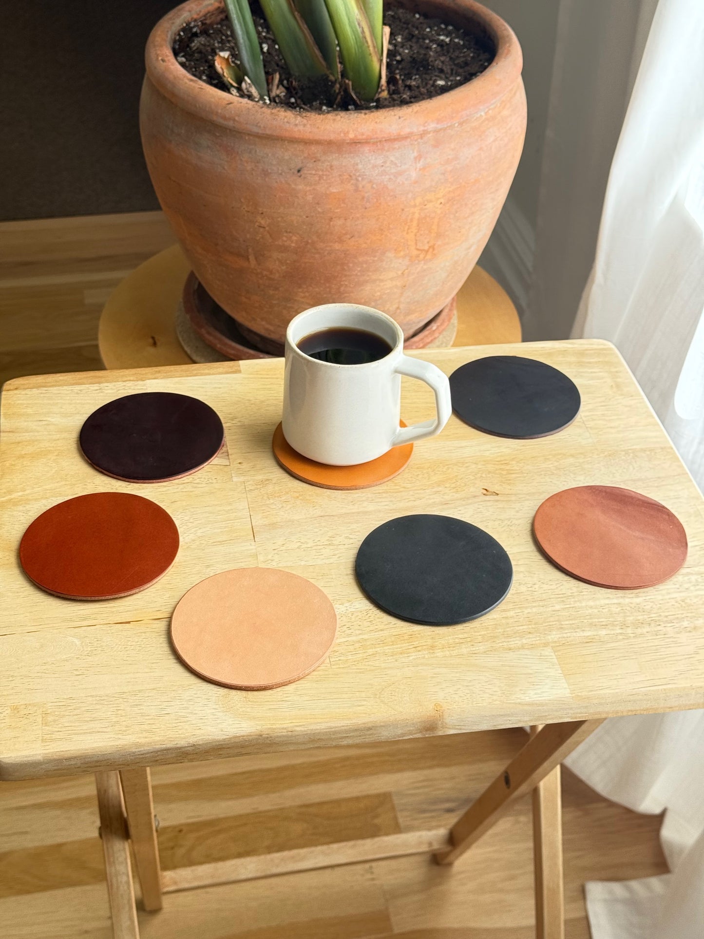 White mug hanging from a wooden board with circular cutouts, next to a potted plant.